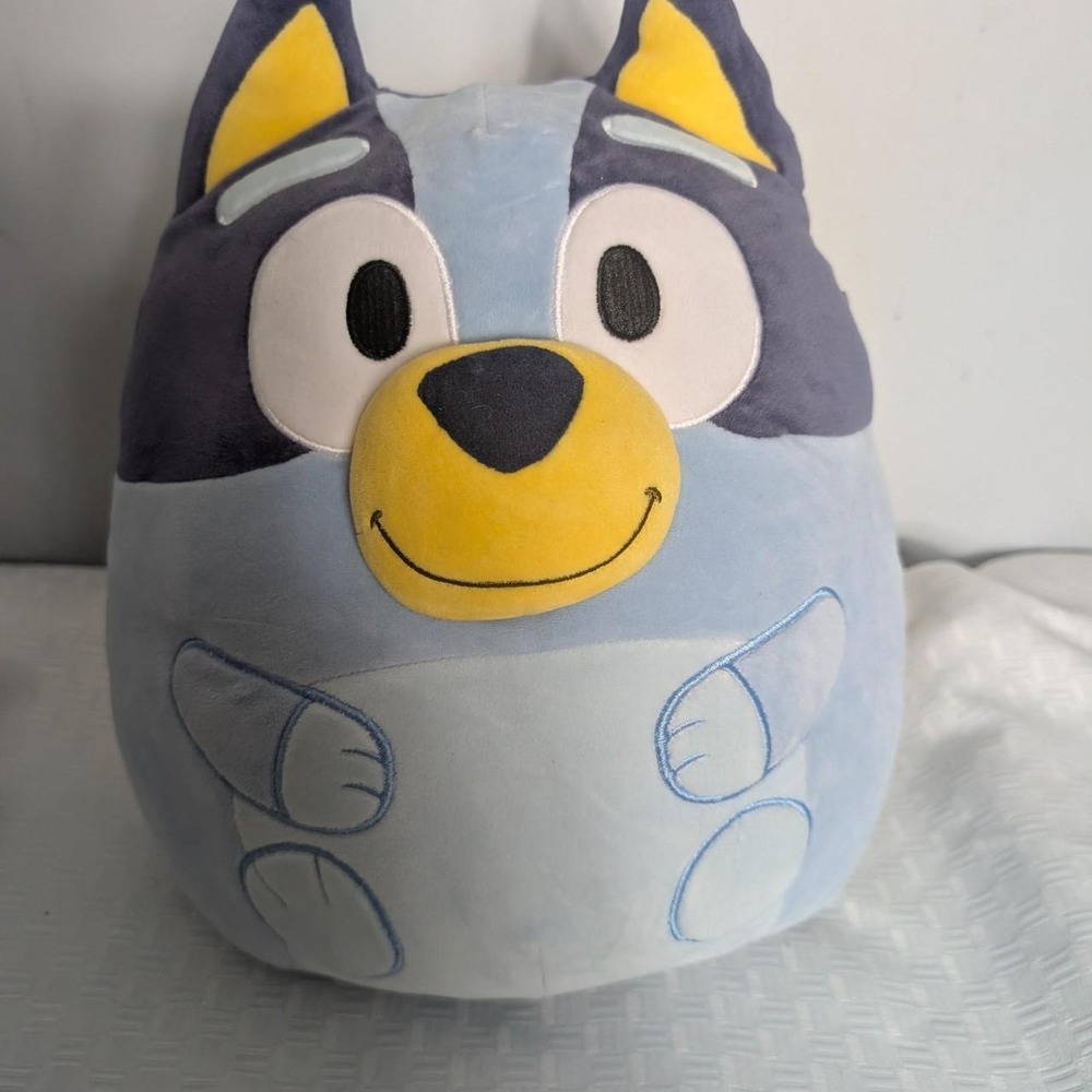 Bluey the dog plush toy. Blue with yellow ears and nose, gray paws and black